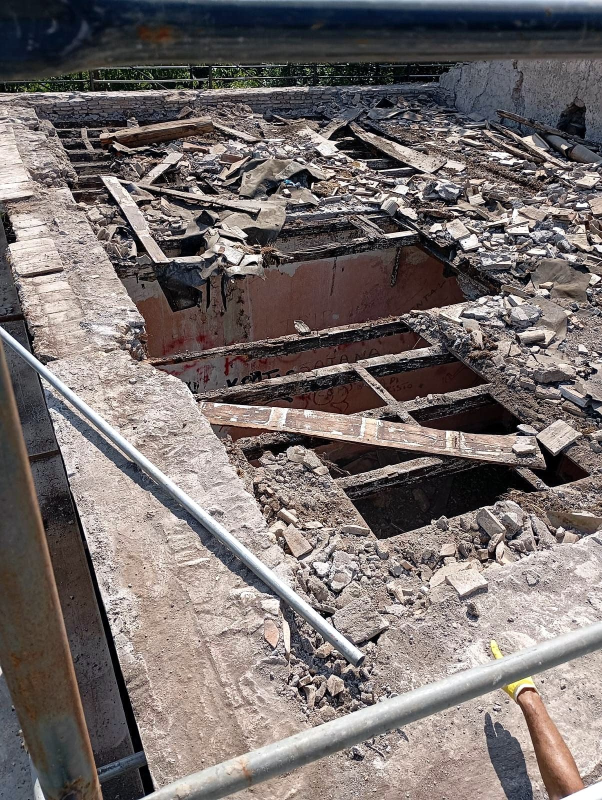 Apertura di solaio con travi lignee esposte e macerie di cantiere